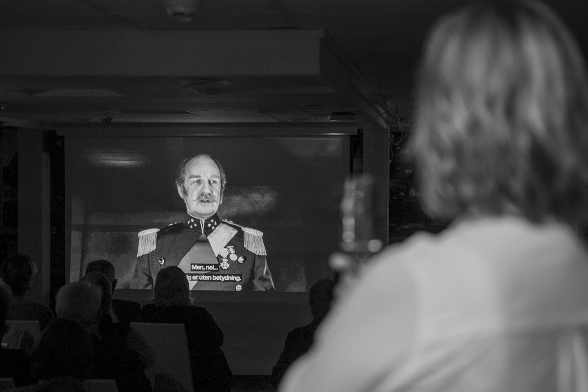 Nærbilde av en gjest som ser på Babettes Gjestebud-filmen under velkomstprogrammet.